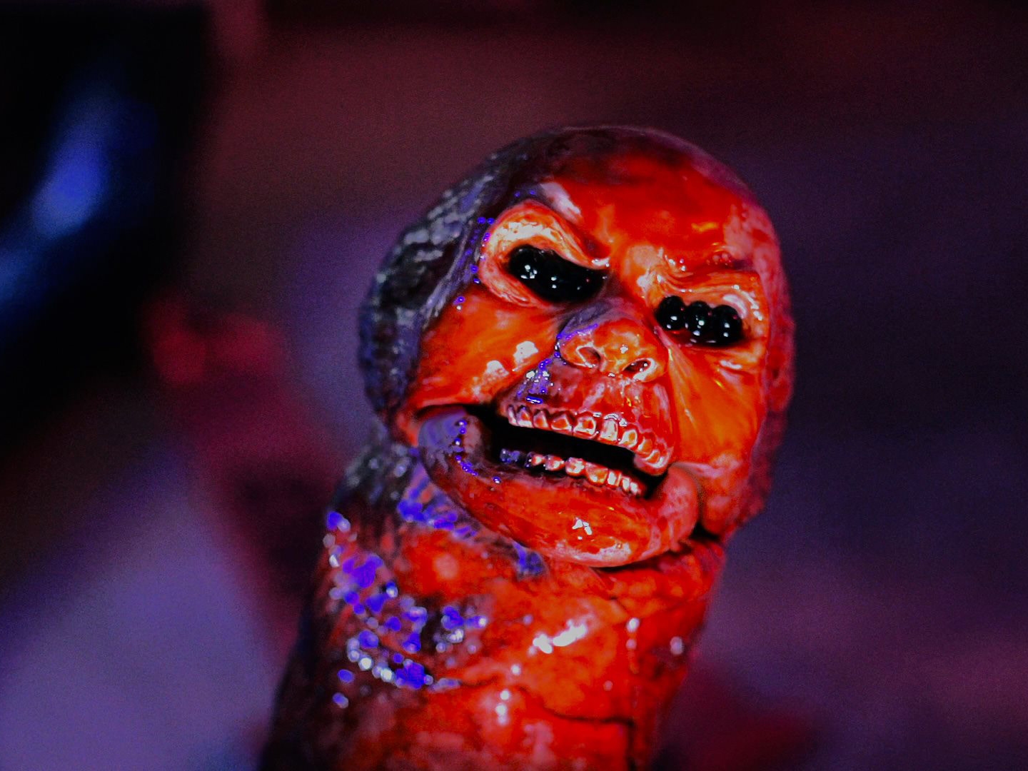 A monstrous alien baby reaches up from the bottom of the image. Its pink body is soaked in the blood of its mother, a terrible creature from beyond space and time and reality, borne into the world.